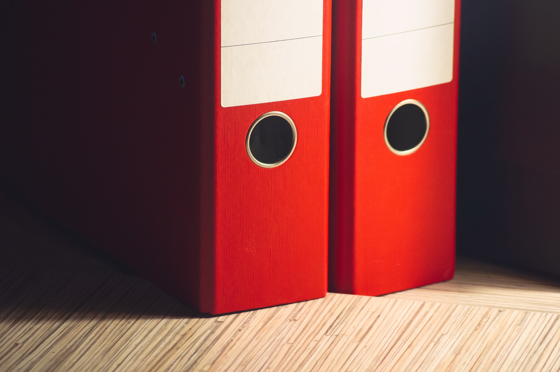 Two red folders standing side by side on wooden surface