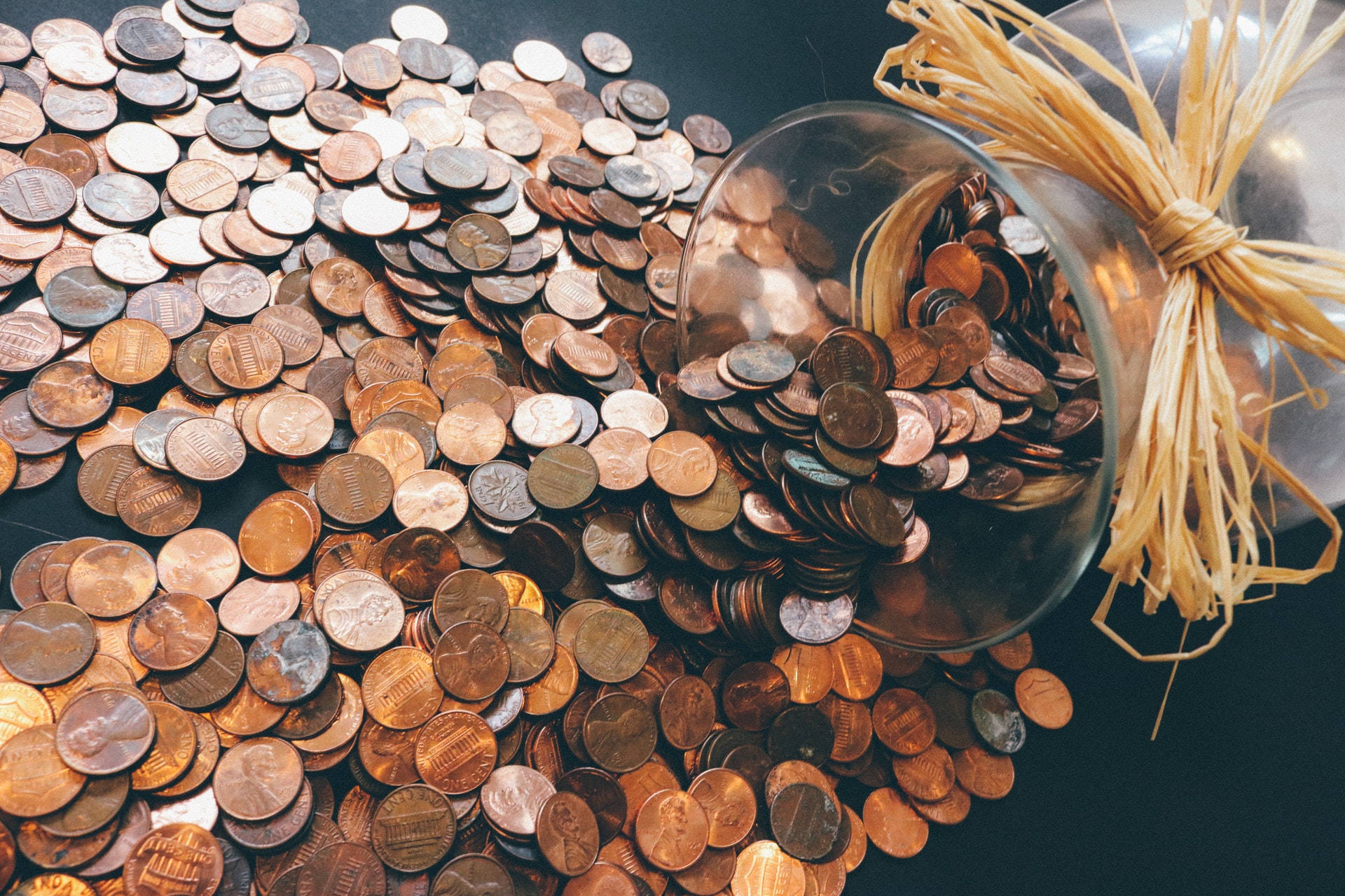 coins spilling onto surface from glass jar