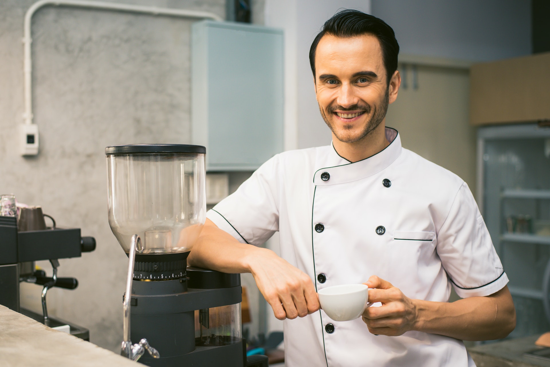 chef standing at coffee maker with cup in hand