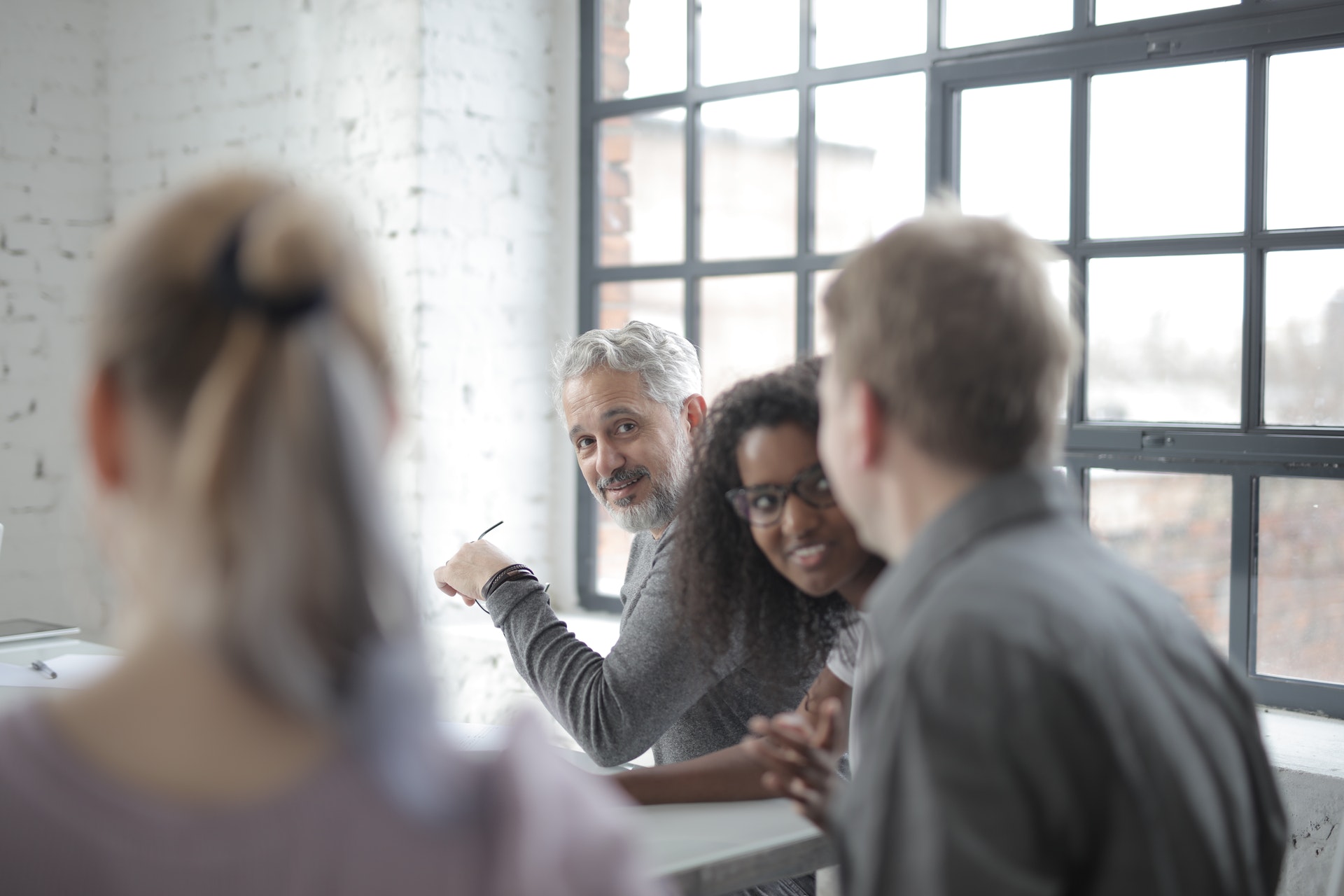 grey-haired man looking at colleagues at table