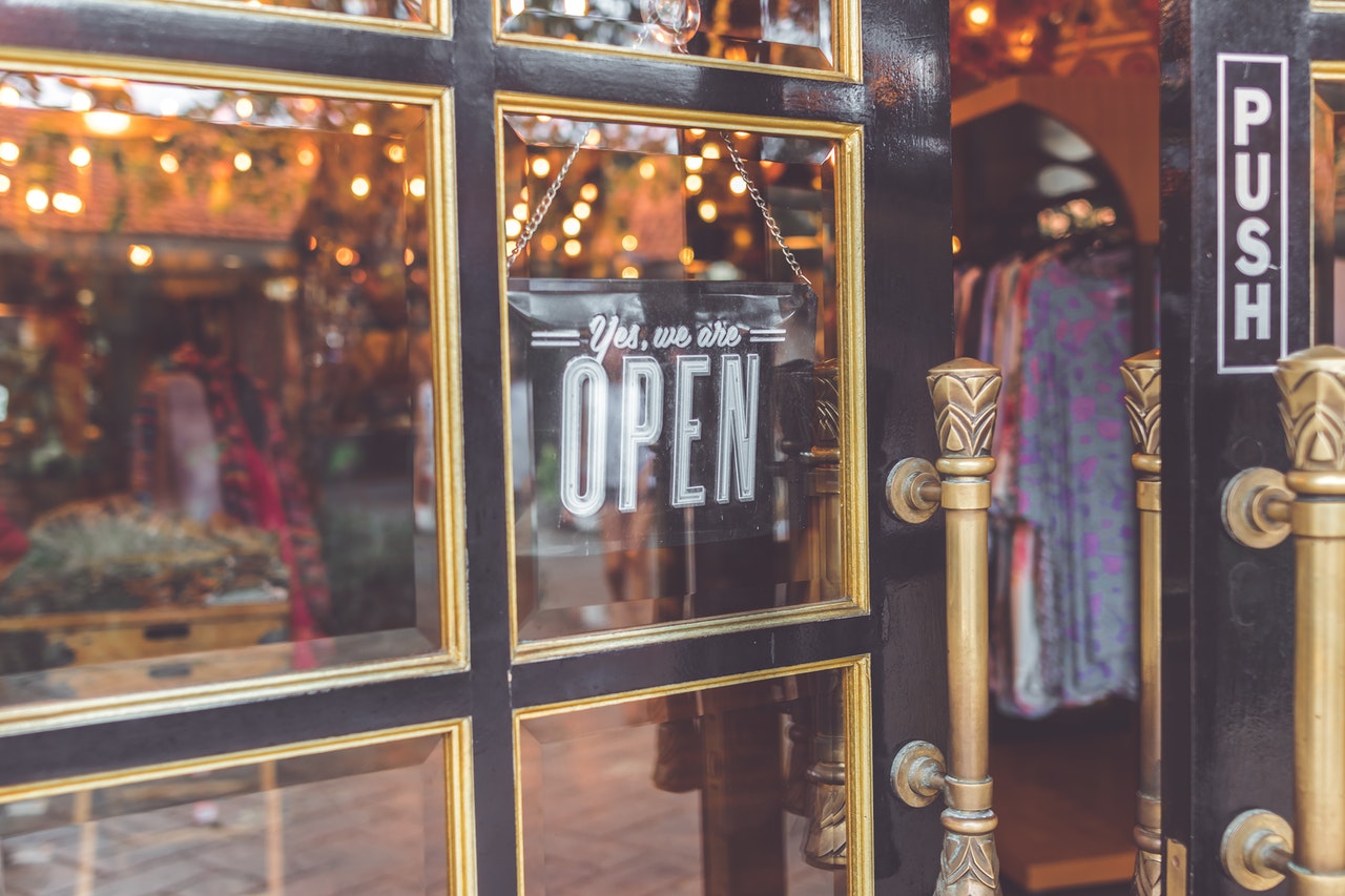 open sign handing in clothing shop door