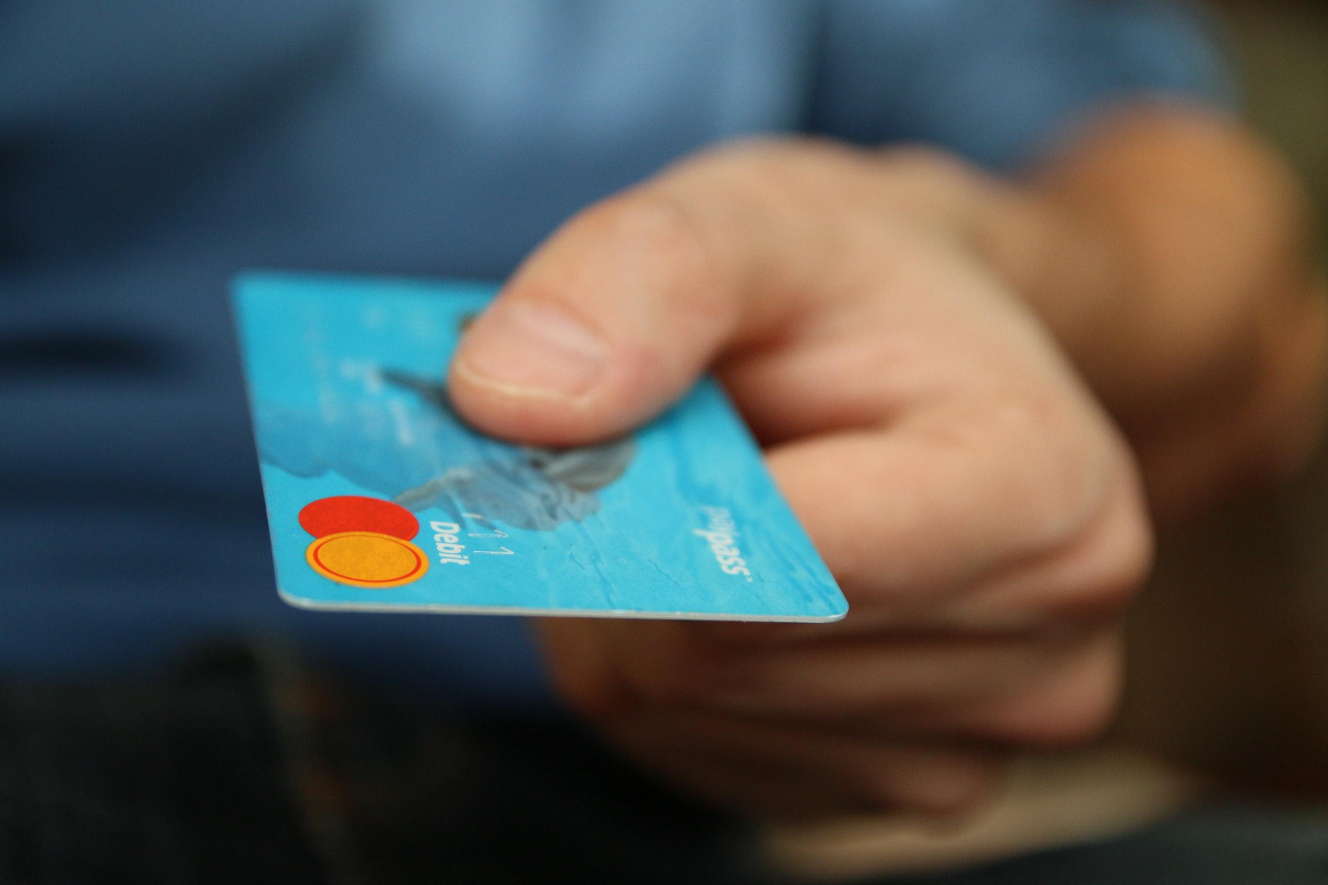 Hand offering up a blue debit card