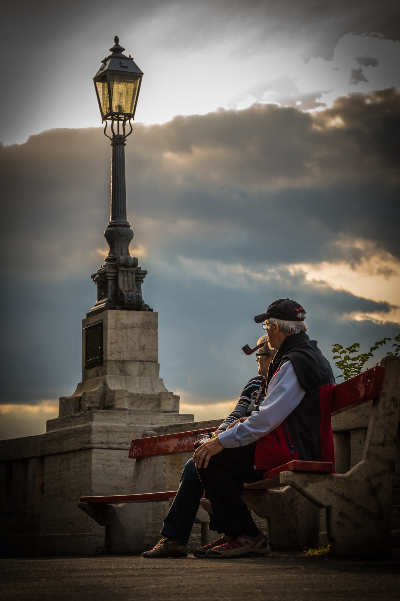 two older people sitting on bench at sunset