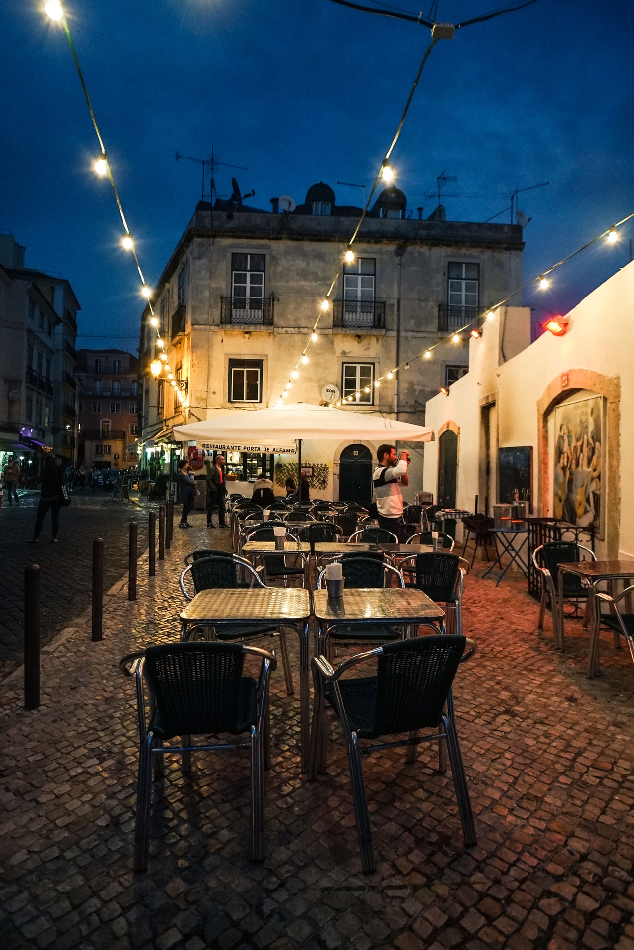 exterior of restaurant with chairs and people walking around