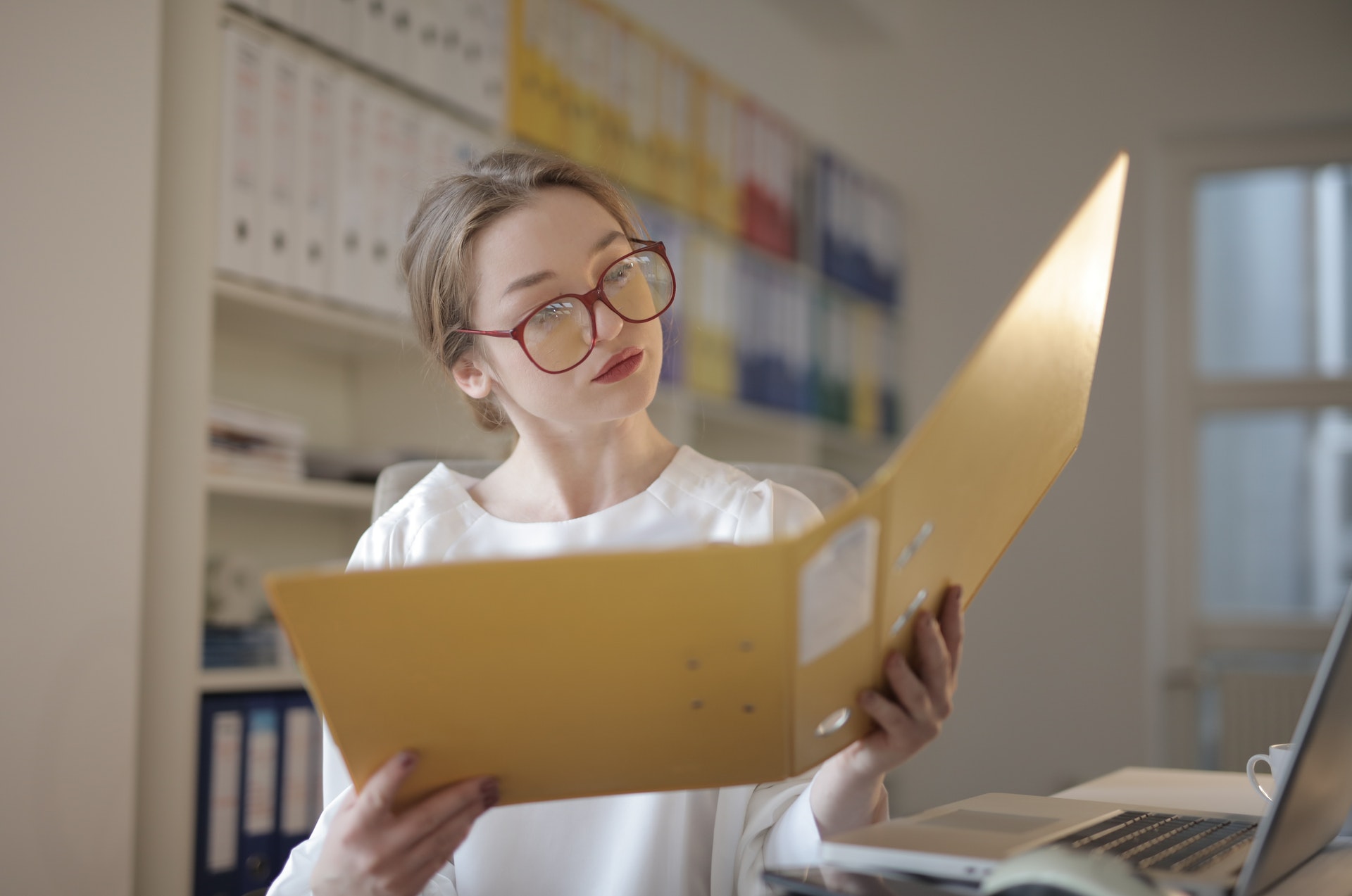 woman with glasses browsing through yellow folder