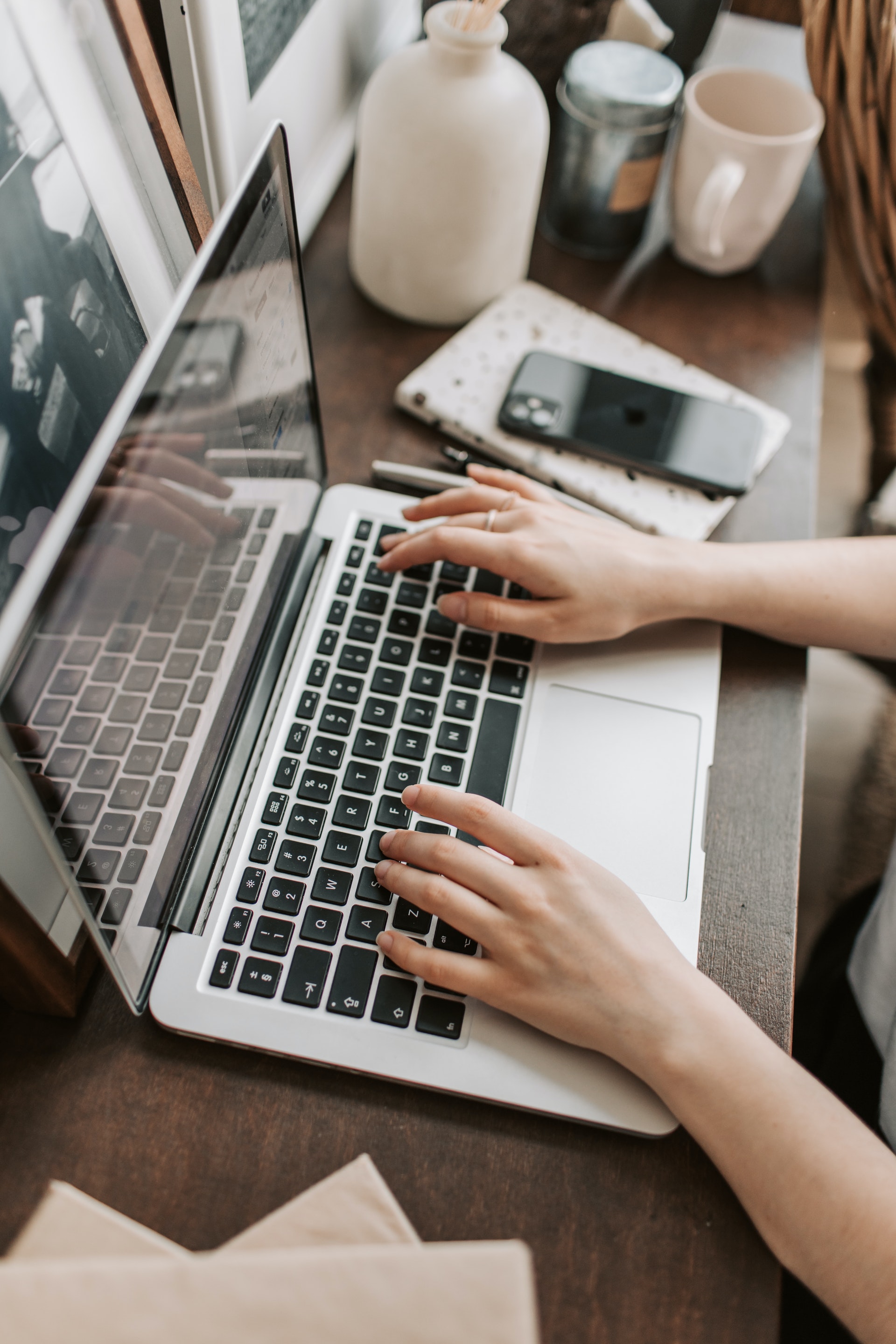 person using macbook on wooden surface