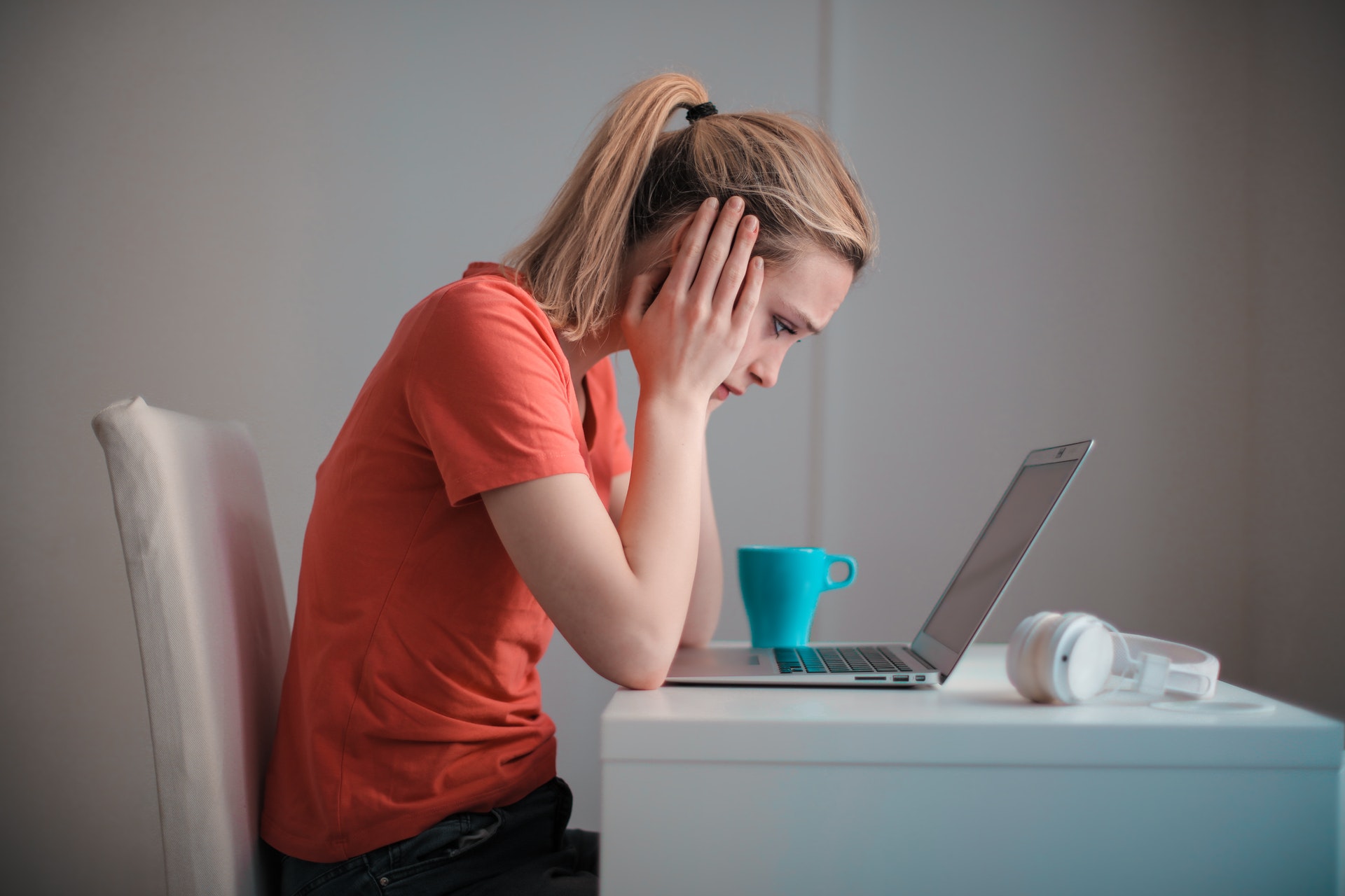 woman with head in her hands behind laptop